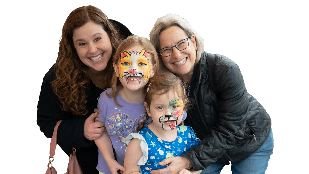 Two children with face paint styled as animals stand with two smiling adults. The group poses together, conveying a joyful atmosphere, typical of arf joybound events.